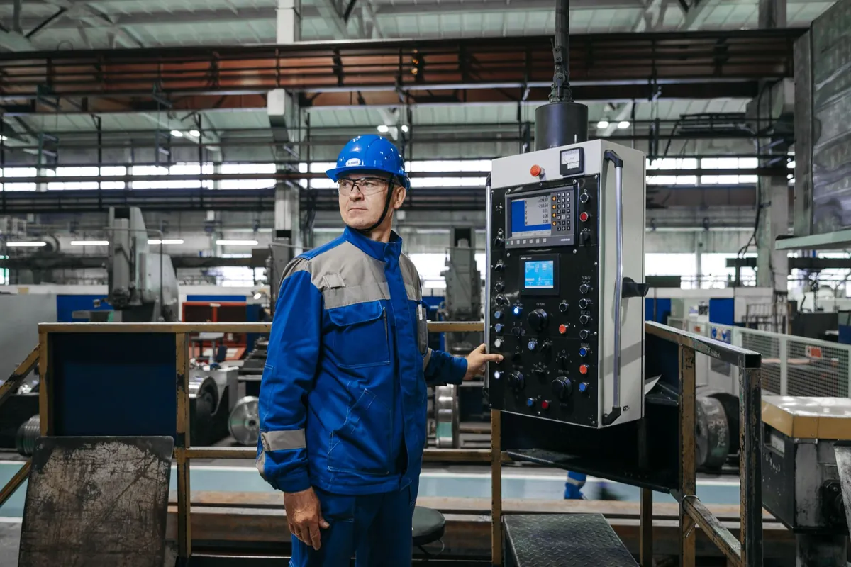 A machine operator at a control panel on a plant floor
