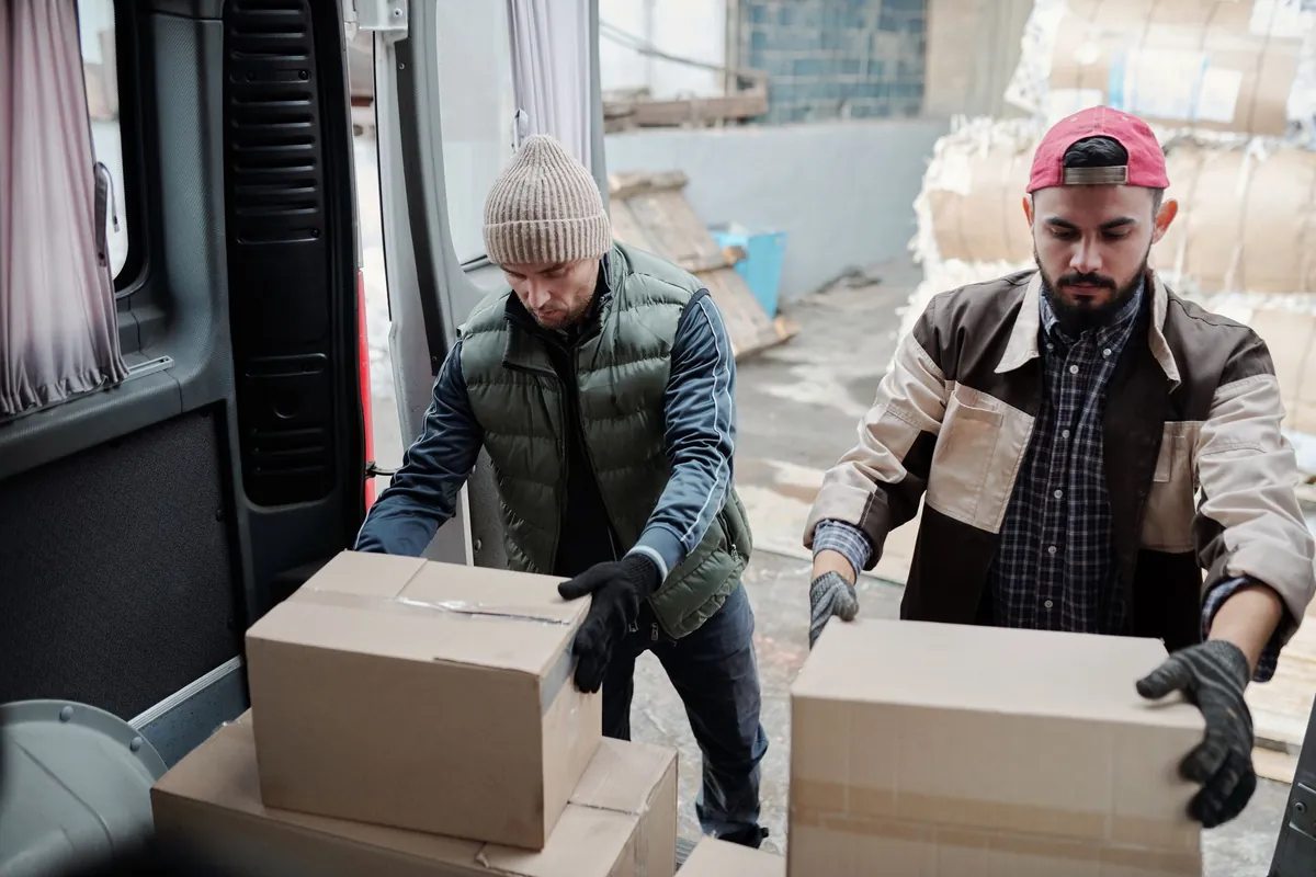 Two warehouse associates lifting boxes onto a delivery van